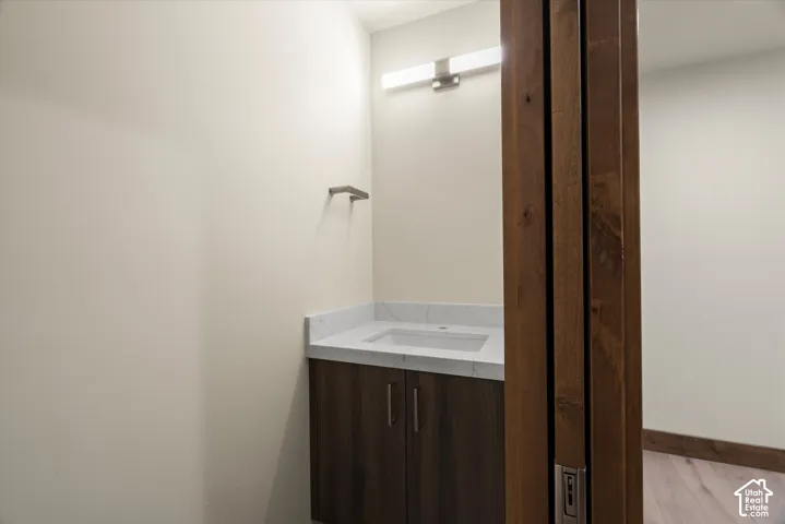 Modern vanity featuring a stone-finish countertop, undermount sink, dark wood-finish cabinetry, and horizontal LED wall-mounted lighting