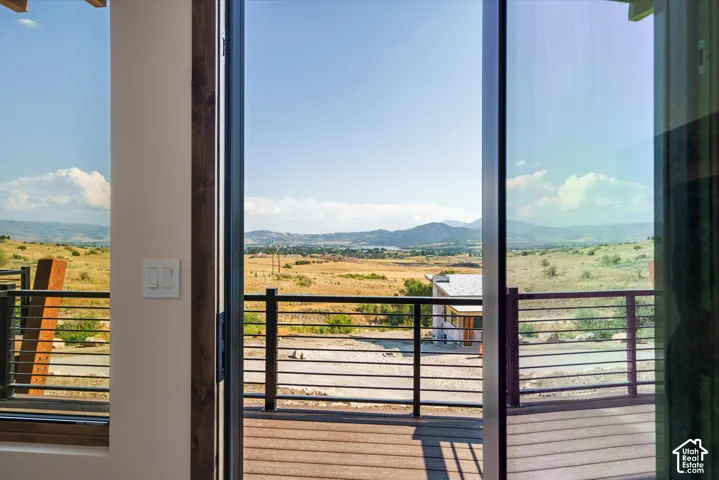 Large sliding glass doors opening to an exterior deck with horizontal metal railings and mountainous landscape scenery