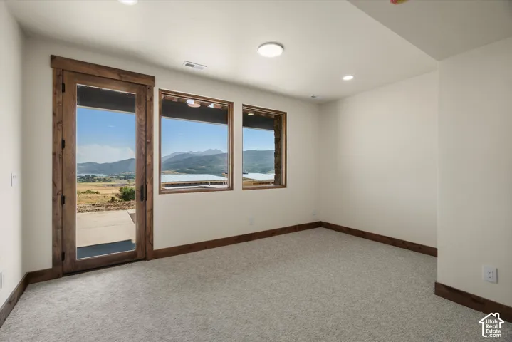 Room featuring wood-trimmed door and window frames, neutral carpeting, recessed ceiling lighting, and mountain scenery