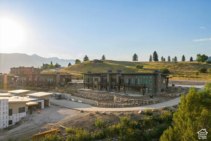 Multi-unit residential complex featuring stacked stone exterior accents, timber framing, metal roofing, expansive window arrays, and terraced rock retaining walls