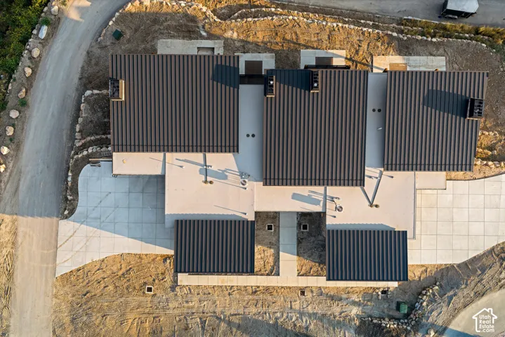 Aerial perspective of a multi-unit residential structure featuring metal roofing, multiple chimneys, and concrete hardscaping