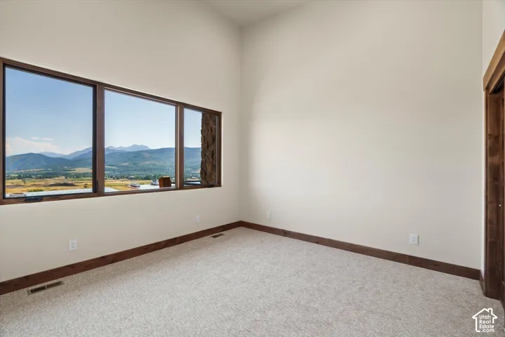 Vaulted ceiling room featuring expansive multi-pane windows, natural stone exterior siding detail, and stained wood window casings