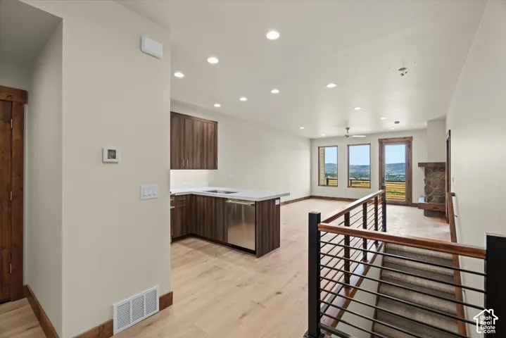Kitchen featuring wood-finish cabinetry, stone-composite countertops, and a stainless steel dishwasher