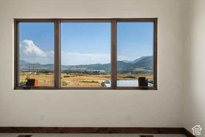 Large tripartite window featuring wood-trimmed casing, showcasing mountain and rural scenery