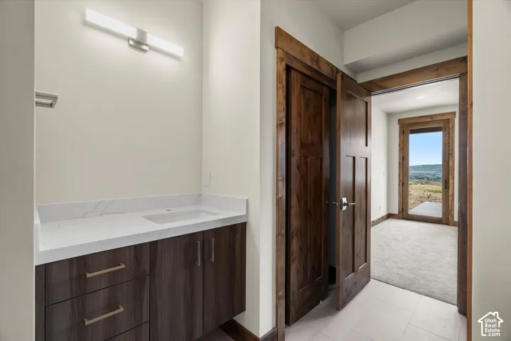 Floating vanity with a quartz countertop, integrated rectangular sink, linear LED wall-mounted lighting, and solid wood-finish cabinetry featuring stained wood door and window casings