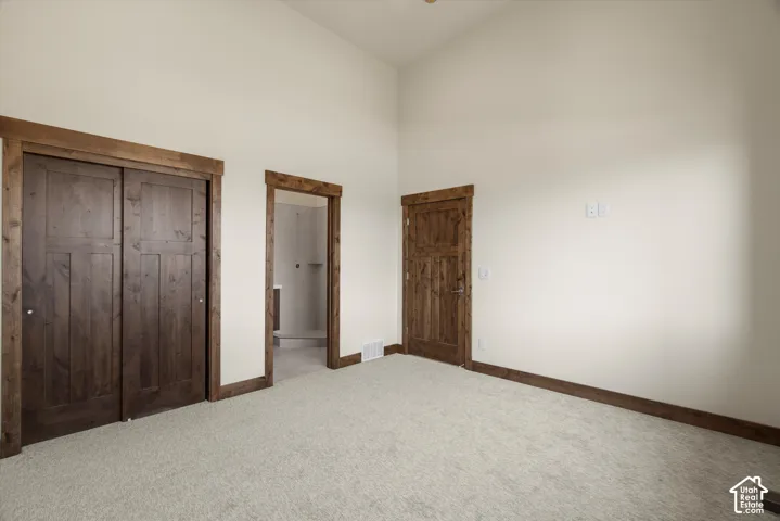 Interior space featuring high vaulted ceilings, textured wall-to-wall carpeting, and stained wood door trim and casing throughout