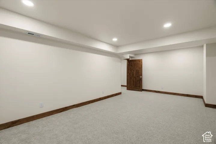 Neutral interior space featuring recessed lighting, wall-to-wall carpeting, wood-trim finishings, and a solid wood door