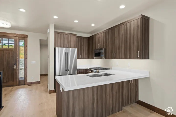 Kitchen featuring wood-finish cabinetry, white countertops, recessed lighting, stainless steel appliances, and wood-finish flooring