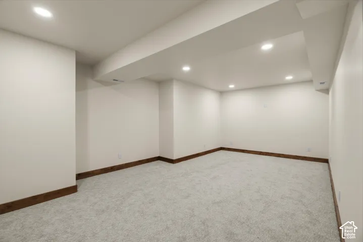Neutral interior space featuring recessed ceiling lighting, light-toned wall-to-wall carpeting, and wood-finish trim