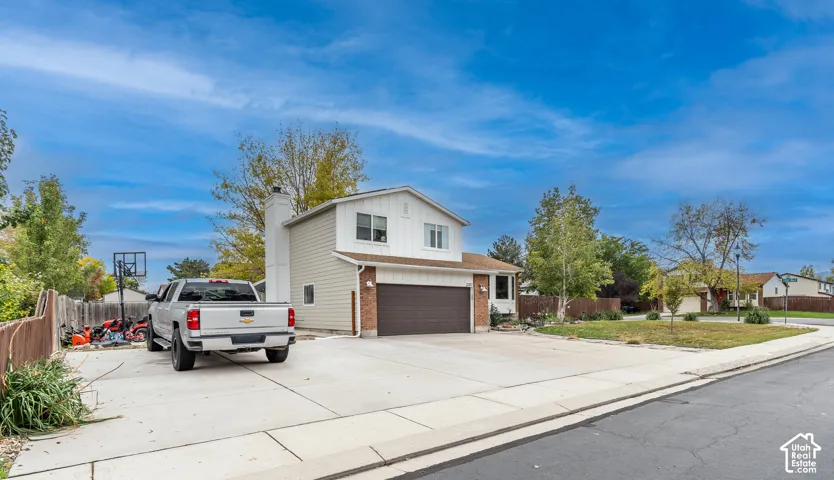 Multi-level exterior featuring brick and horizontal siding, an attached two-car garage, and an expansive concrete driveway