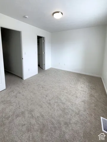 Master bedroom. Neutral-toned carpeting, crisp white walls, flush-mount ceiling light fixture, and closet with hinged door