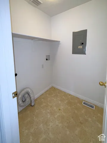 Utility area featuring durable vinyl flooring, wall-mounted electrical panel, and built-in upper shelving