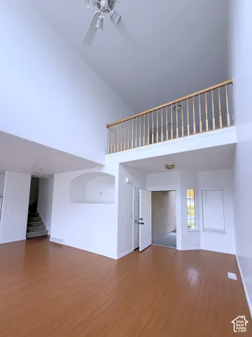 Vaulted ceilings, wood-finish flooring, recessed wall niche, and balcony with wooden balustrade