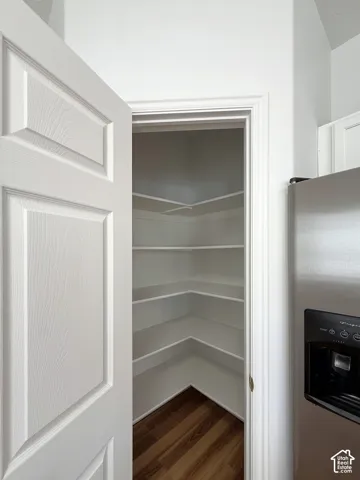 Pantry featuring white tiered shelving and wood-finish flooring