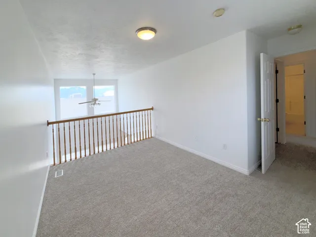 Interior space featuring wall-to-wall carpeting, wood railing balustrade, and ceiling-mounted lighting fixtures