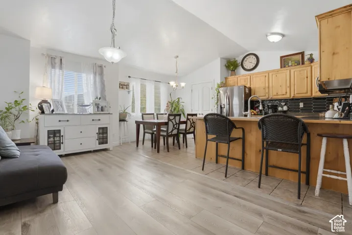 Kitchen featuring wood-finish cabinetry, stainless steel refrigerator, tile backsplash, and wood-finish flooring