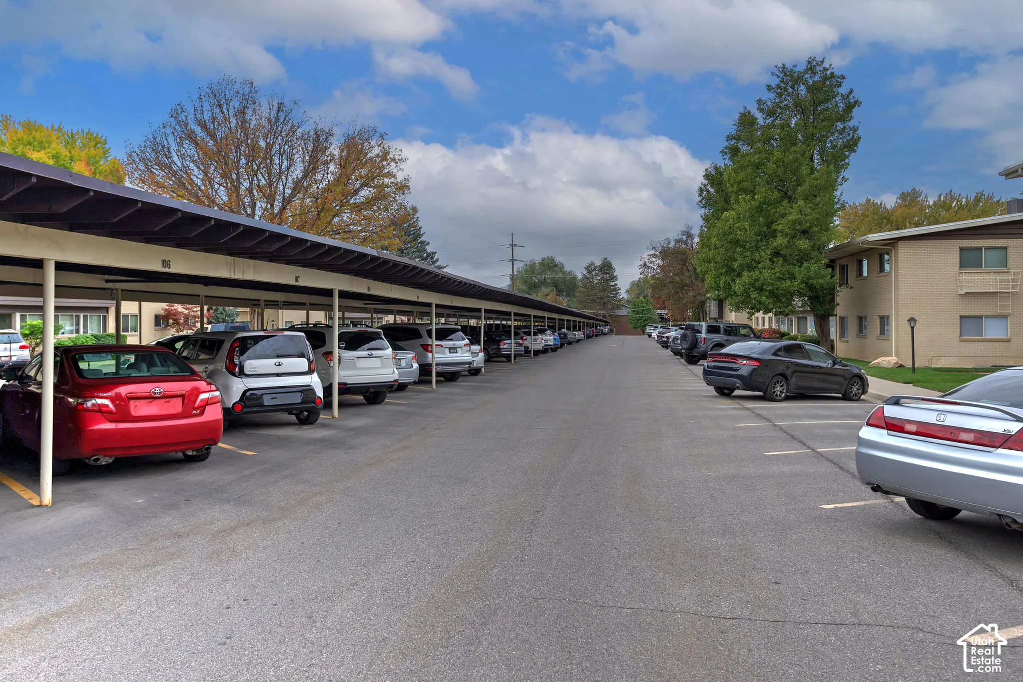 Asphalt surface parking area featuring covered carport structures and marked parking spaces