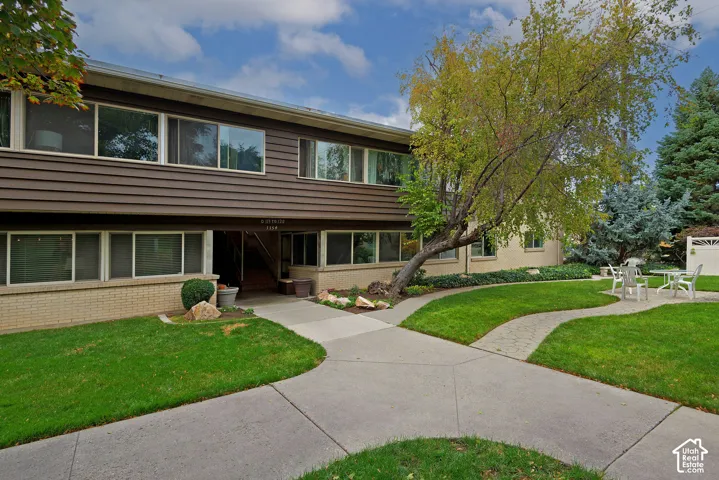 Multi-level exterior featuring horizontal siding, brick masonry, concrete walkways, and manicured landscaping with mature trees