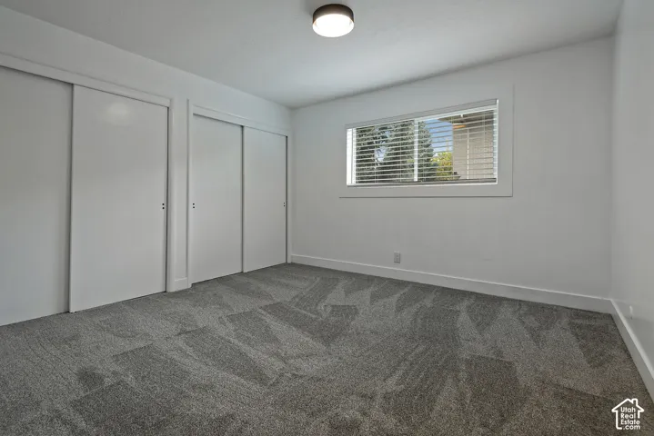 Neutral-toned carpeting, dual closets with sliding doors, a horizontal sliding window, and a modern circular ceiling light fixture
