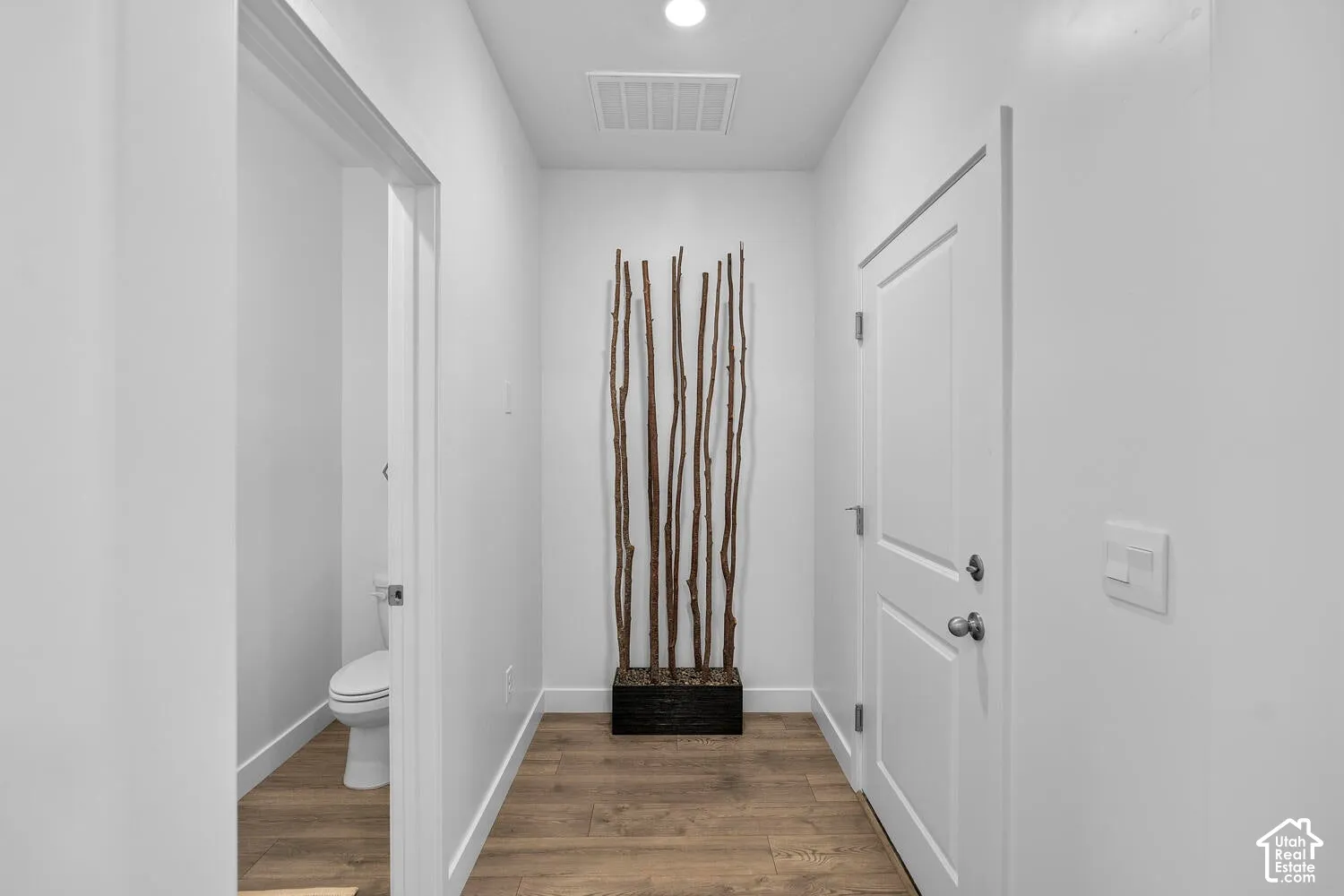 Hallway featuring wood-finish flooring, recessed ceiling lighting, and a multi-panel door