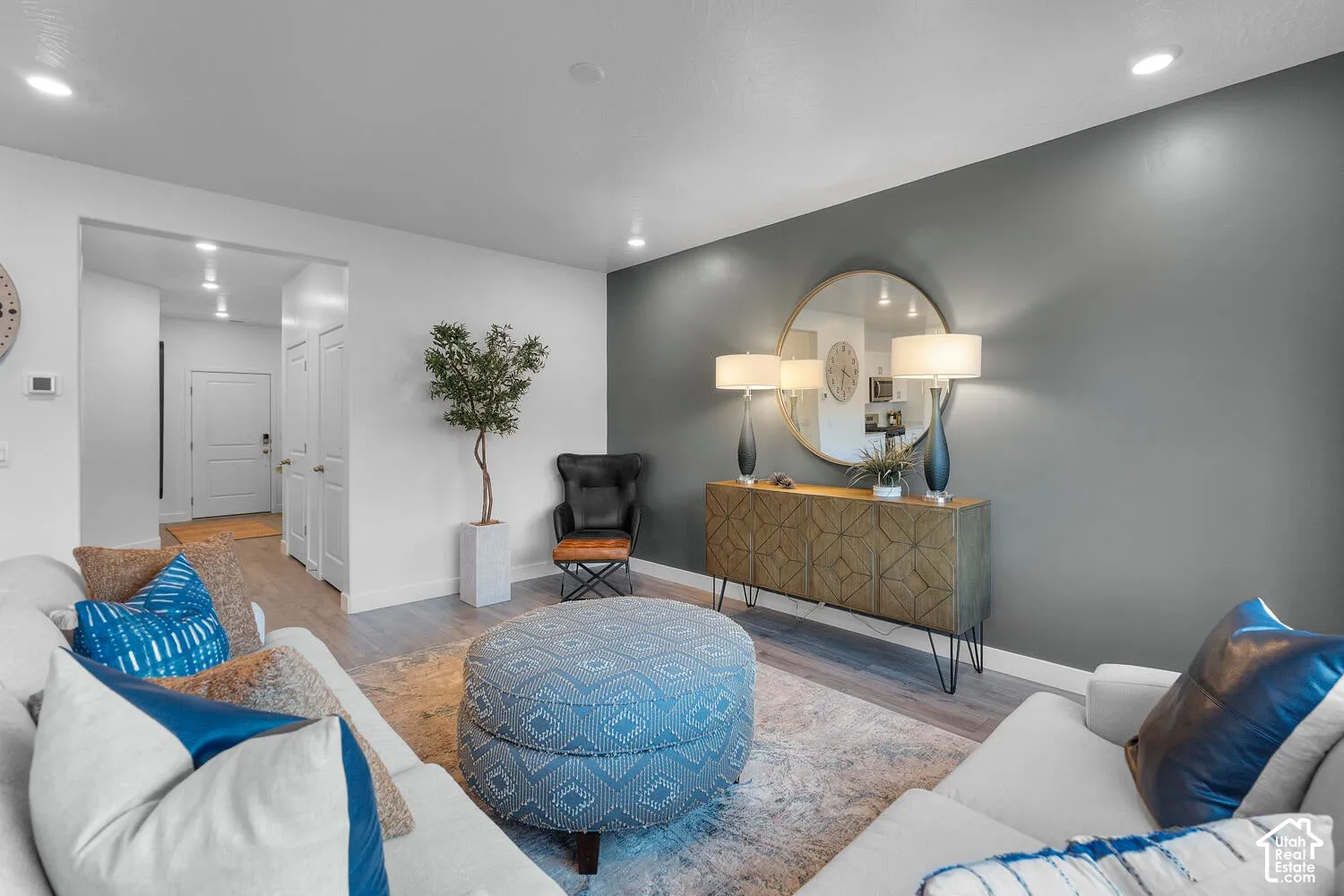 Living area featuring wood-finish flooring, recessed lighting, and a charcoal-toned accent wall