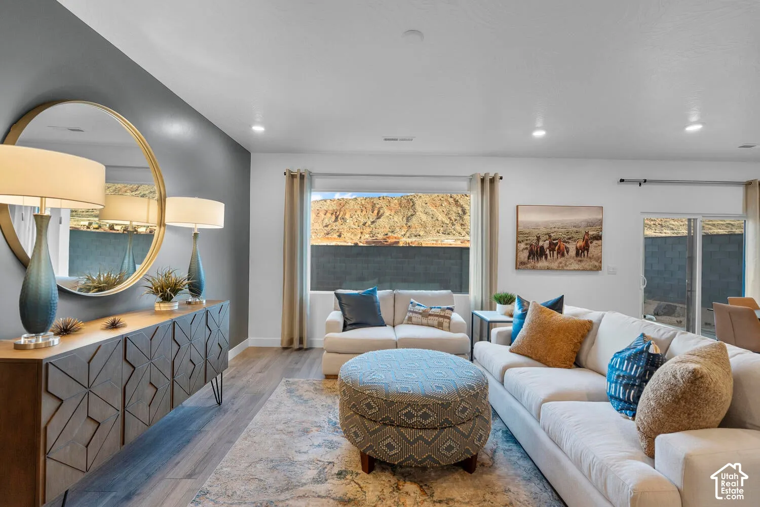 Living area featuring wood-finish flooring, a charcoal accent wall, recessed lighting, and a large window with desert landscape backdrop