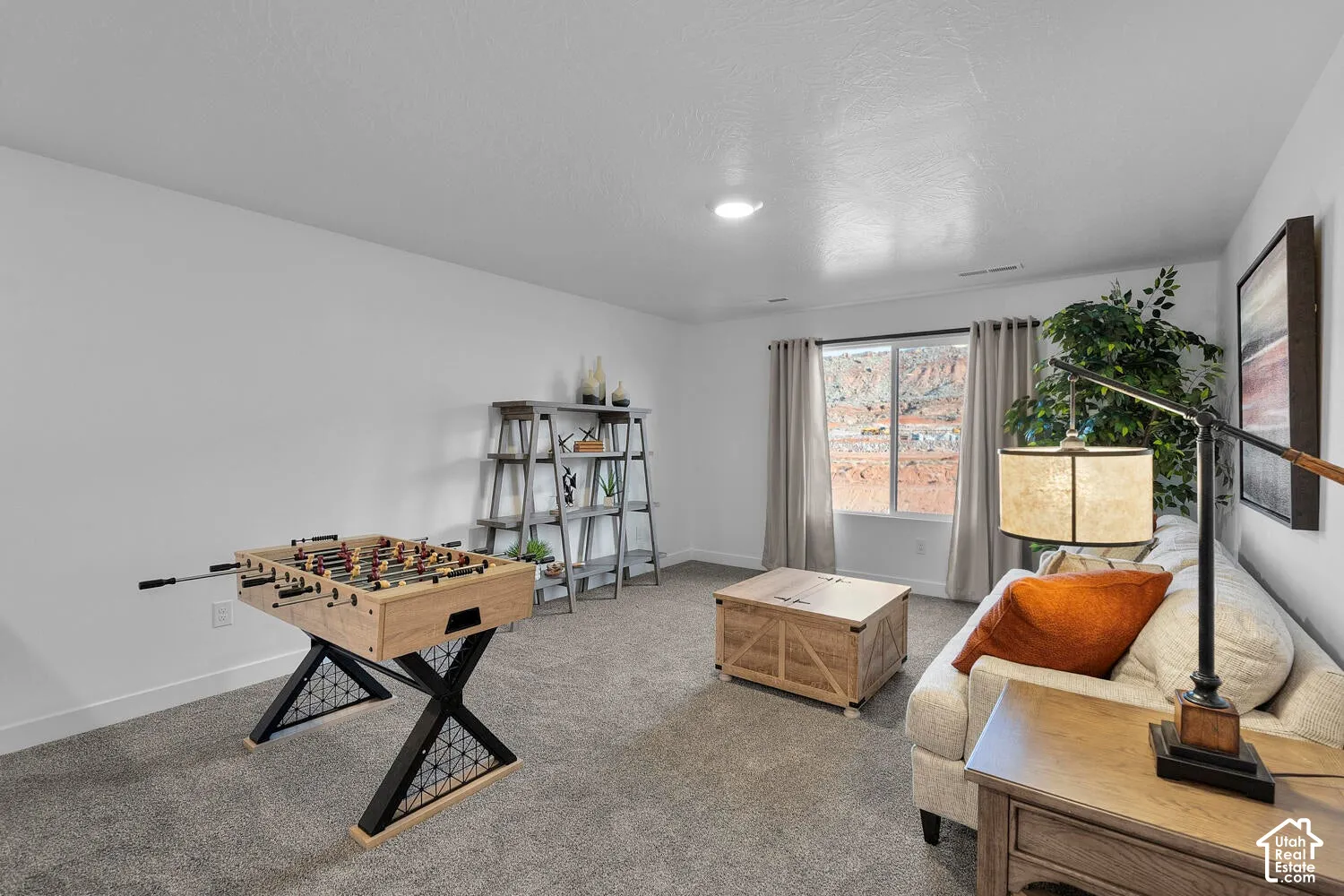 Neutral-toned room featuring neutral wall-to-wall carpeting, crisp white walls, and a large window showcasing a natural rock landscape