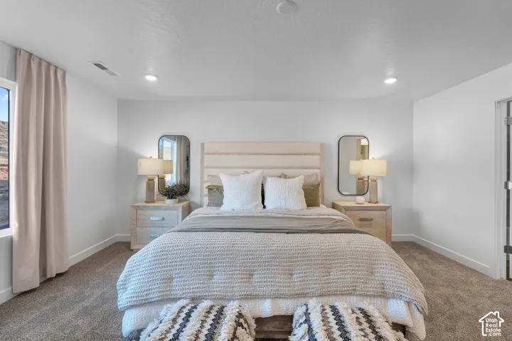 Bedroom with neutral-toned carpeting, recessed ceiling lighting, and rounded rectangular wall mirrors