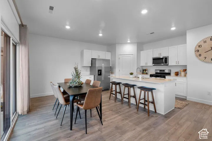 Kitchen featuring white cabinetry, an expansive island with a countertop, stainless steel appliances, and wood-finish flooring