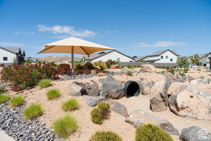 Xeriscape grounds featuring a shade sail, boulder landscaping, native plantings, and decorative rock beds