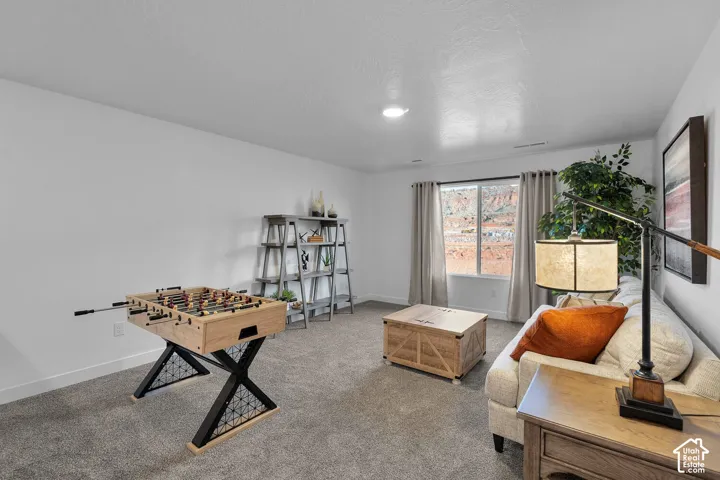 Neutral-toned room featuring neutral wall-to-wall carpeting, crisp white walls, and a large window showcasing a natural rock landscape