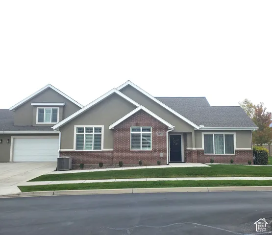 Multi-gabled exterior featuring brick masonry siding, dual-tone facade, attached multi-car garage, and concrete driveway