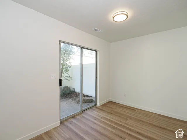 Interior space featuring wood-finish flooring, neutral wall tones, flush-mount ceiling lighting, and a sliding glass door providing exterior access
