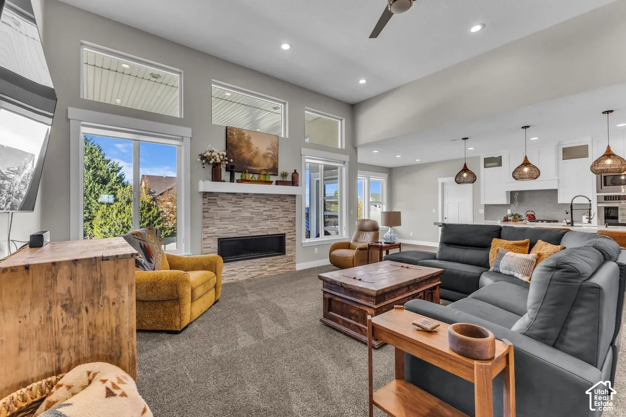 Vaulted ceilings with recessed lighting, floor-to-ceiling stone-surround fireplace, transom windows, and open-concept design featuring pendant lighting