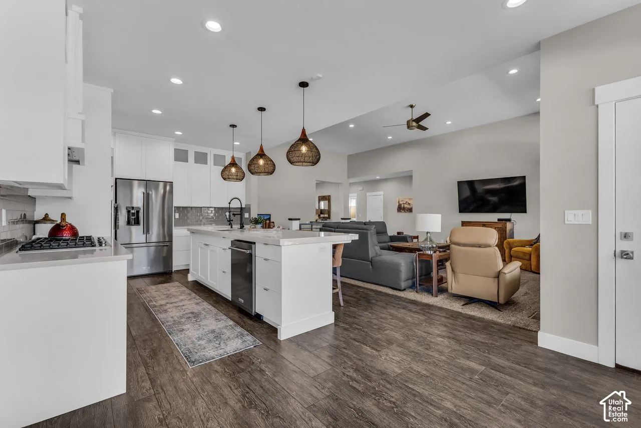 Kitchen featuring white cabinetry, an expansive center island with quartz countertops, wood-finish flooring, recessed lighting, and woven pendant fixtures