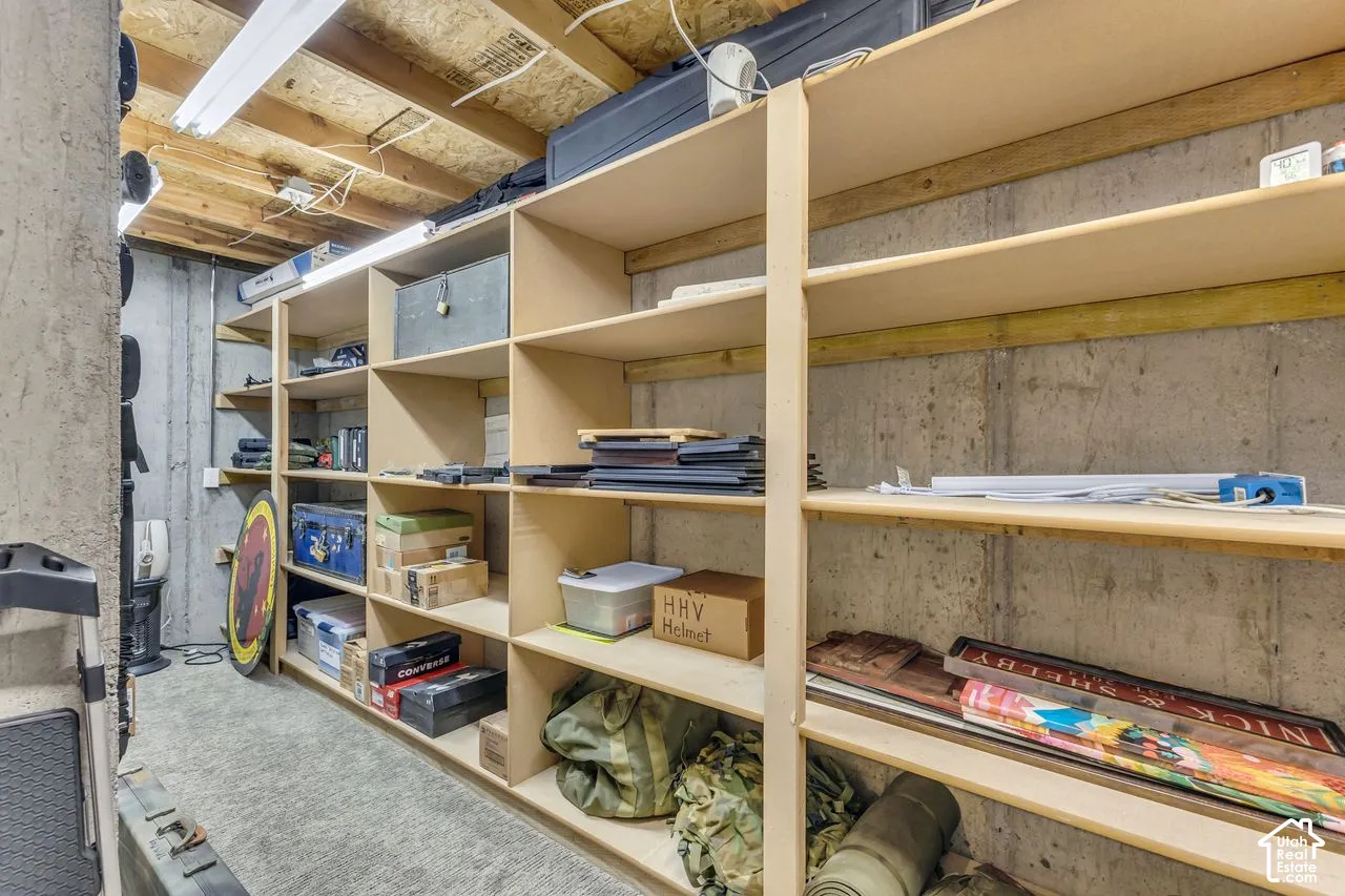 Concrete foundation walls with expansive, wall-to-wall built-in wooden shelving units and exposed ceiling joists