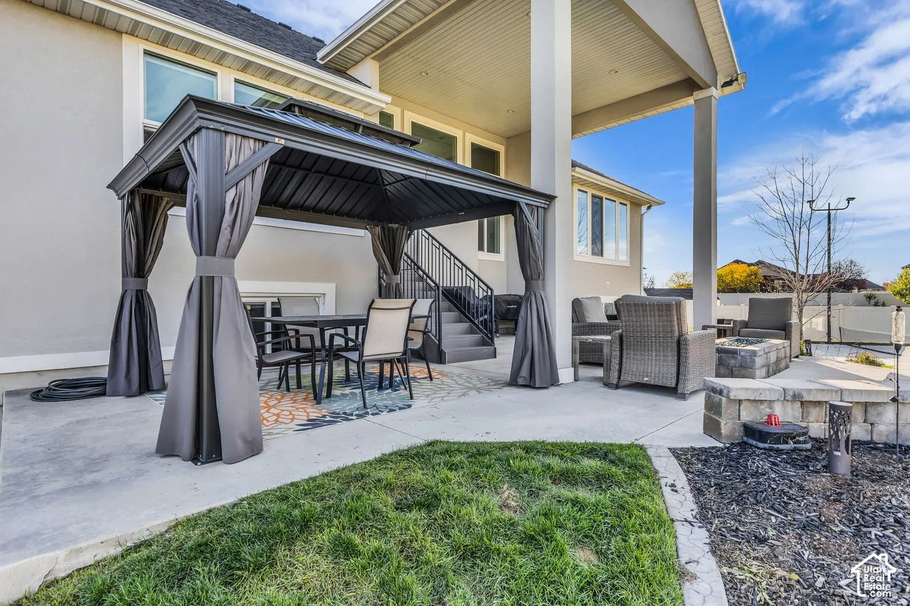 Covered patio featuring concrete flooring, a stone-block retaining wall, and metal stairs with railings