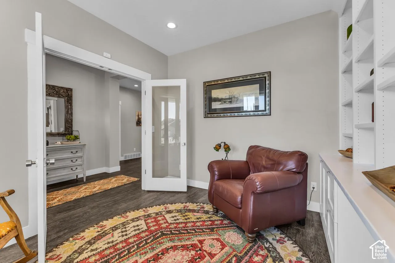 Room featuring wood-finish flooring, white built-in cabinetry with shelving, recessed lighting, and a white French door with glass panels