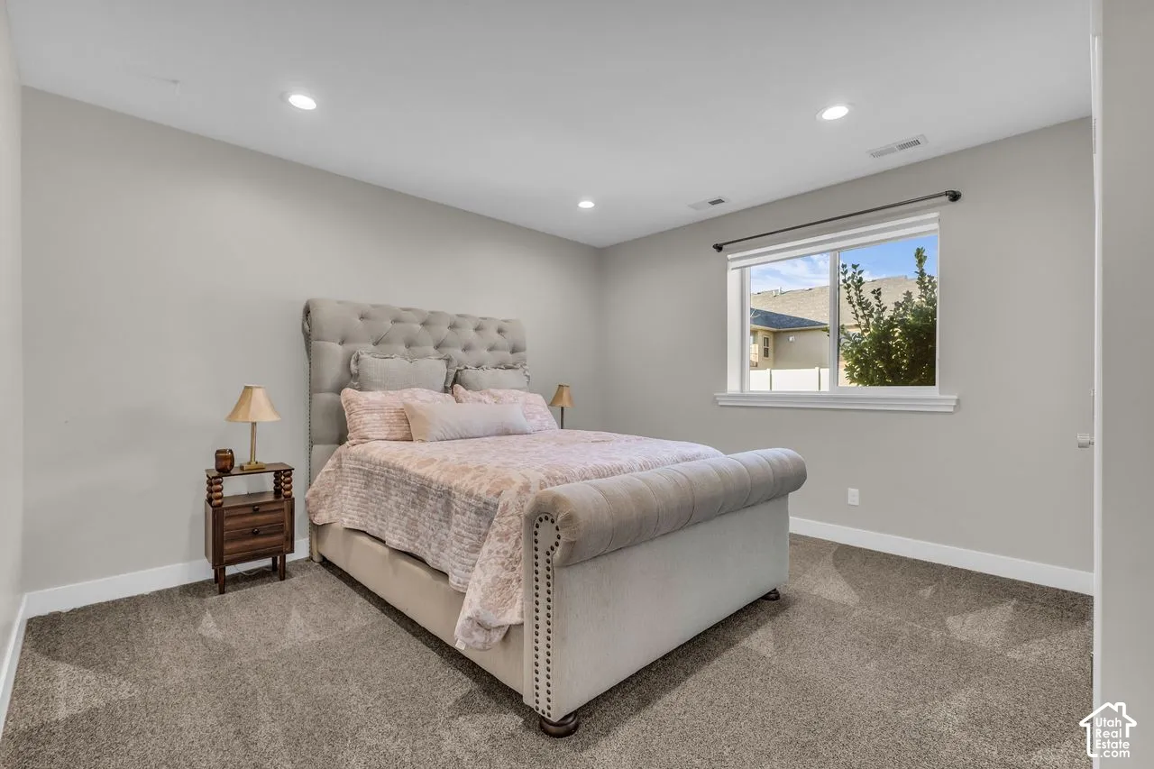 Neutral-toned interior room featuring wall-to-wall carpeting, recessed ceiling lighting, and a window with casing trim