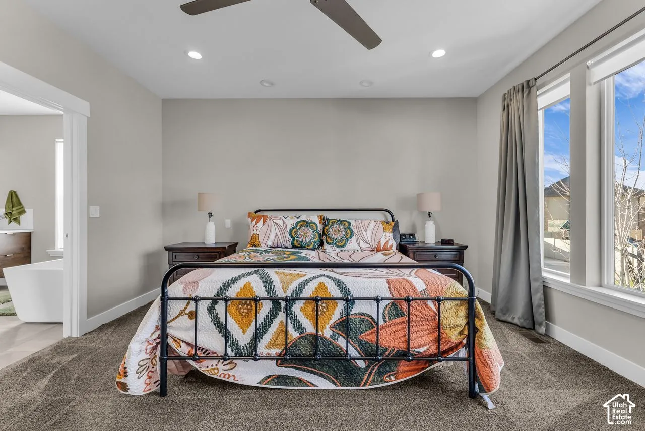 Neutral-toned walls, recessed lighting, multi-blade ceiling fan, wall-to-wall carpeting, and large windows with natural illumination