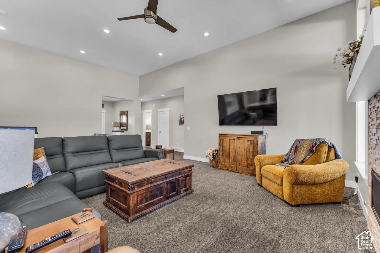 Vaulted ceilings, recessed lighting, ceiling fan, and floor-to-ceiling stone fireplace surround