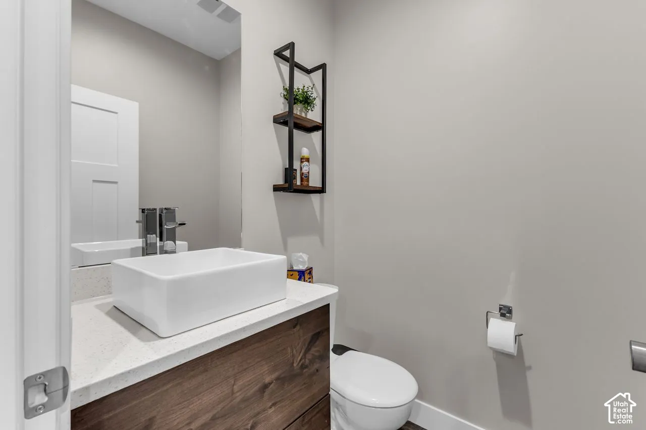 Modern floating vanity with a wood-finish cabinet, rectangular vessel sink, solid-surface countertop, and wall-mounted metal shelving unit