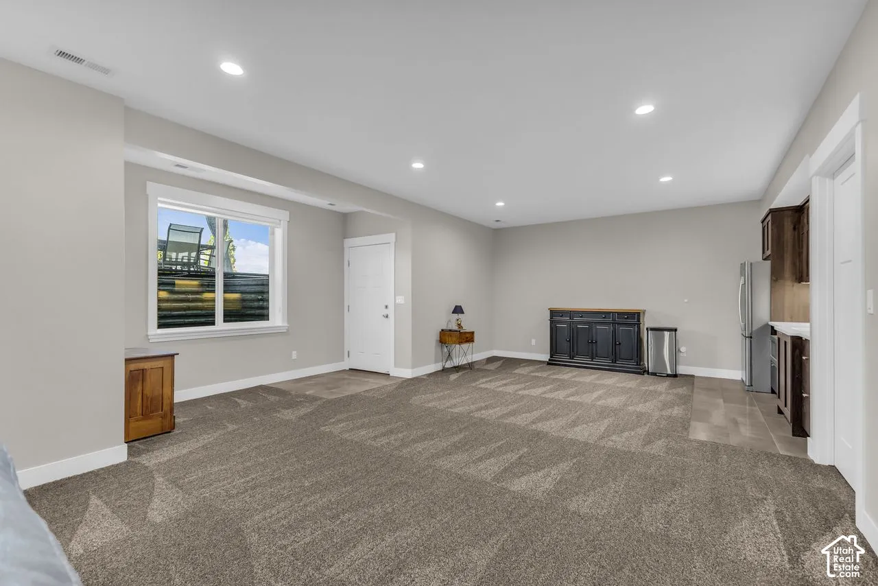 Open-concept area featuring recessed lighting, wall-to-wall carpeting, tile flooring, and built-in kitchenette cabinetry