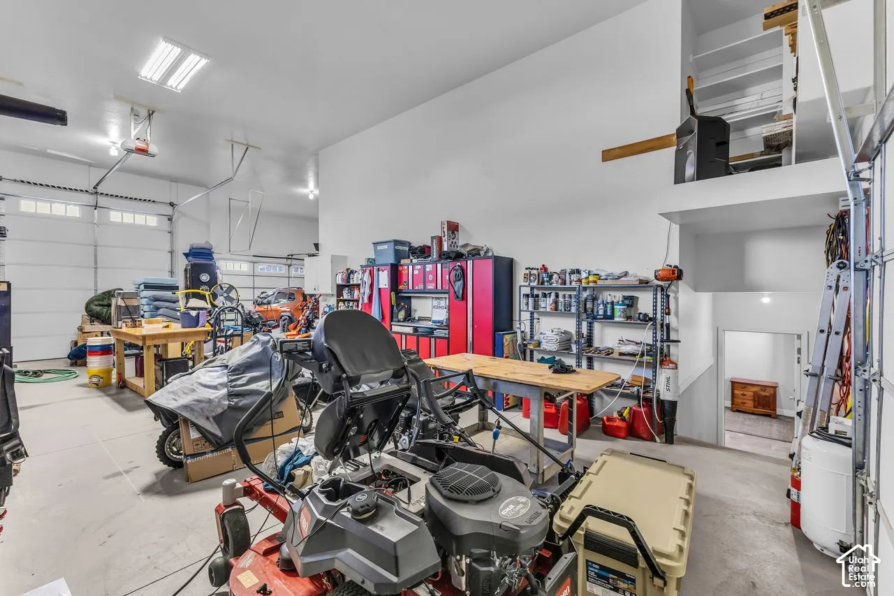Oversized garage featuring high ceilings, fluorescent overhead lighting, two roll-up garage doors, and built-in upper-level storage