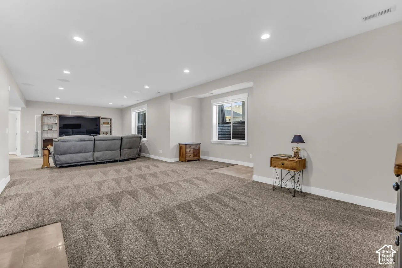 Open-concept room featuring wall-to-wall carpeting, recessed ceiling lighting, and multiple sliding windows