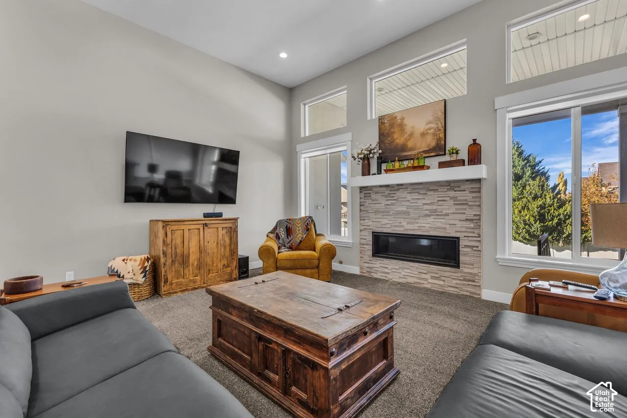 High ceilings, stacked stone fireplace surround, linear electric fireplace, transom windows, and neutral wall color