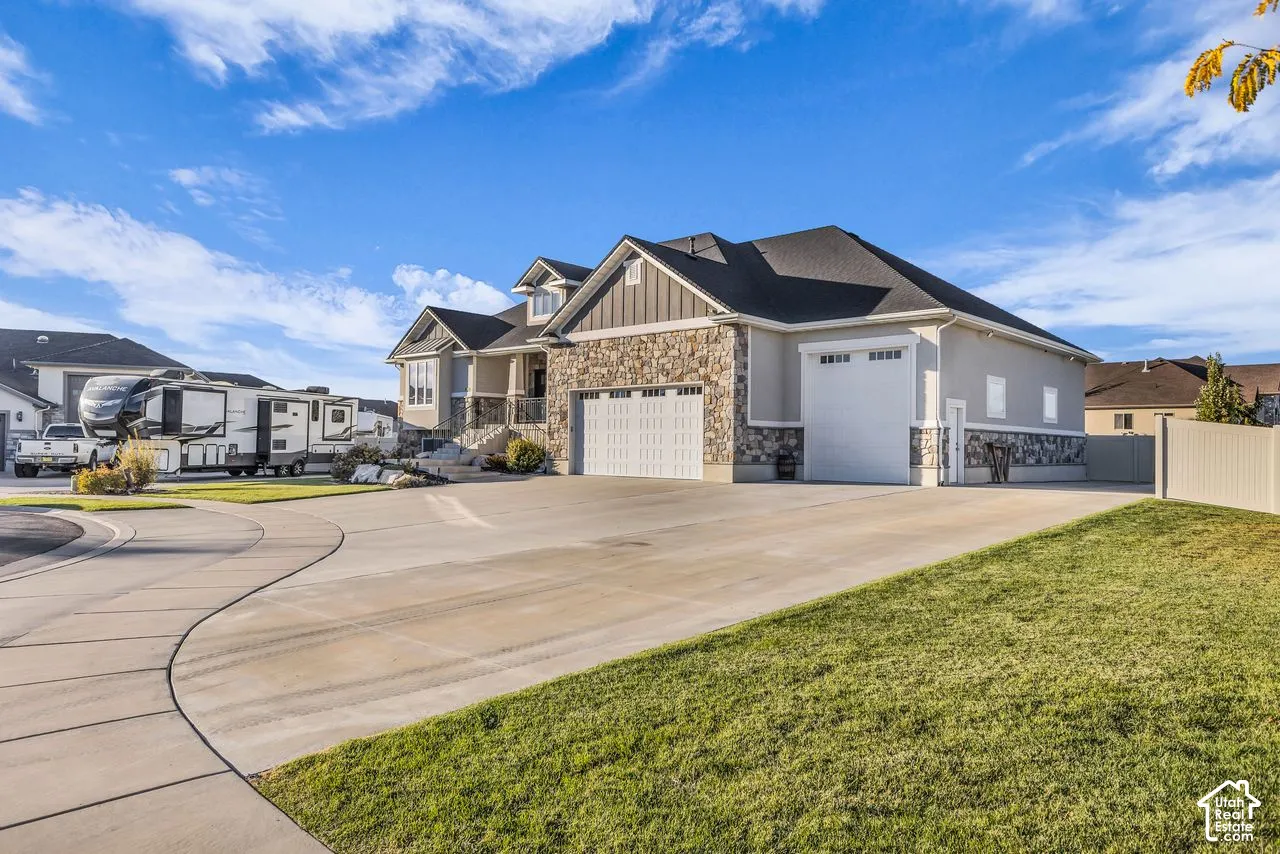 Exterior featuring a stone and siding facade, multi-car garage, concrete driveway, and covered front entry