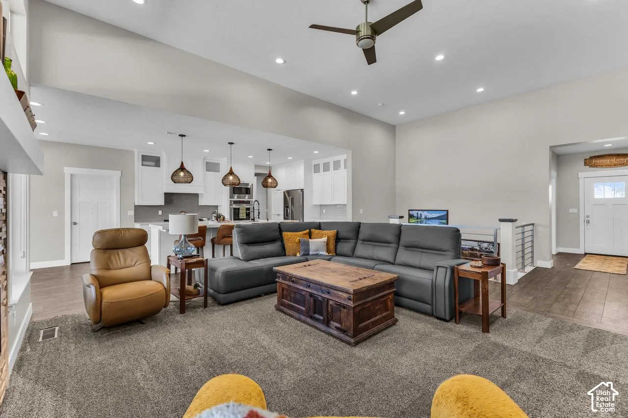 Vaulted ceilings with recessed lighting, wood-finish flooring, white cabinetry, pendant lighting, and metal stair railing