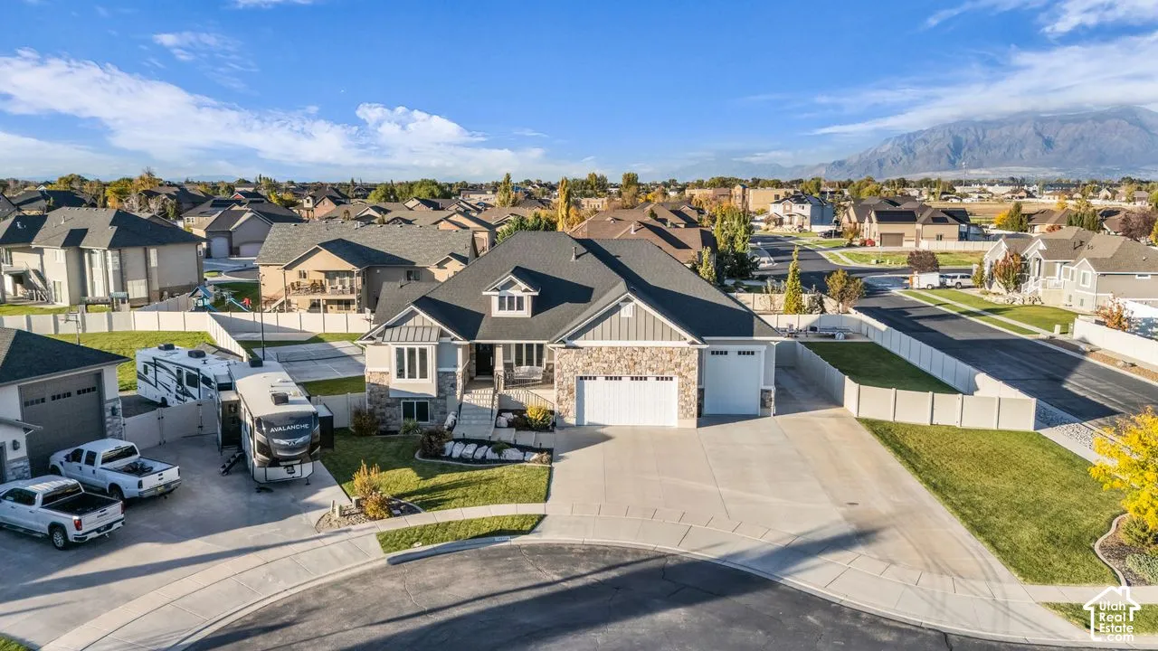 Single-family residence featuring a stone and siding exterior, an attached multi-car garage, concrete driveway, and mountain backdrop