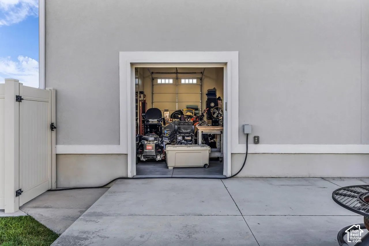 Stucco exterior featuring a garage entry, concrete patio, and white vinyl privacy fencing